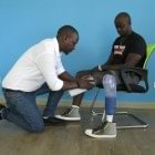 The technician helps the amputee put on his prosthesis.