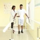 The therapist performs a balance exercise at the parallel bars with a prosthesis wearer.